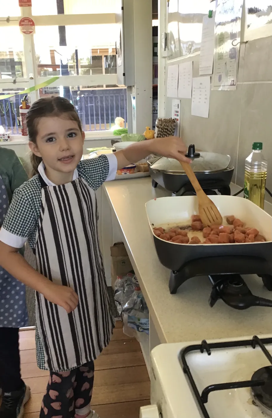 A Carra student in an apron cooking at the stove in the school kitchen