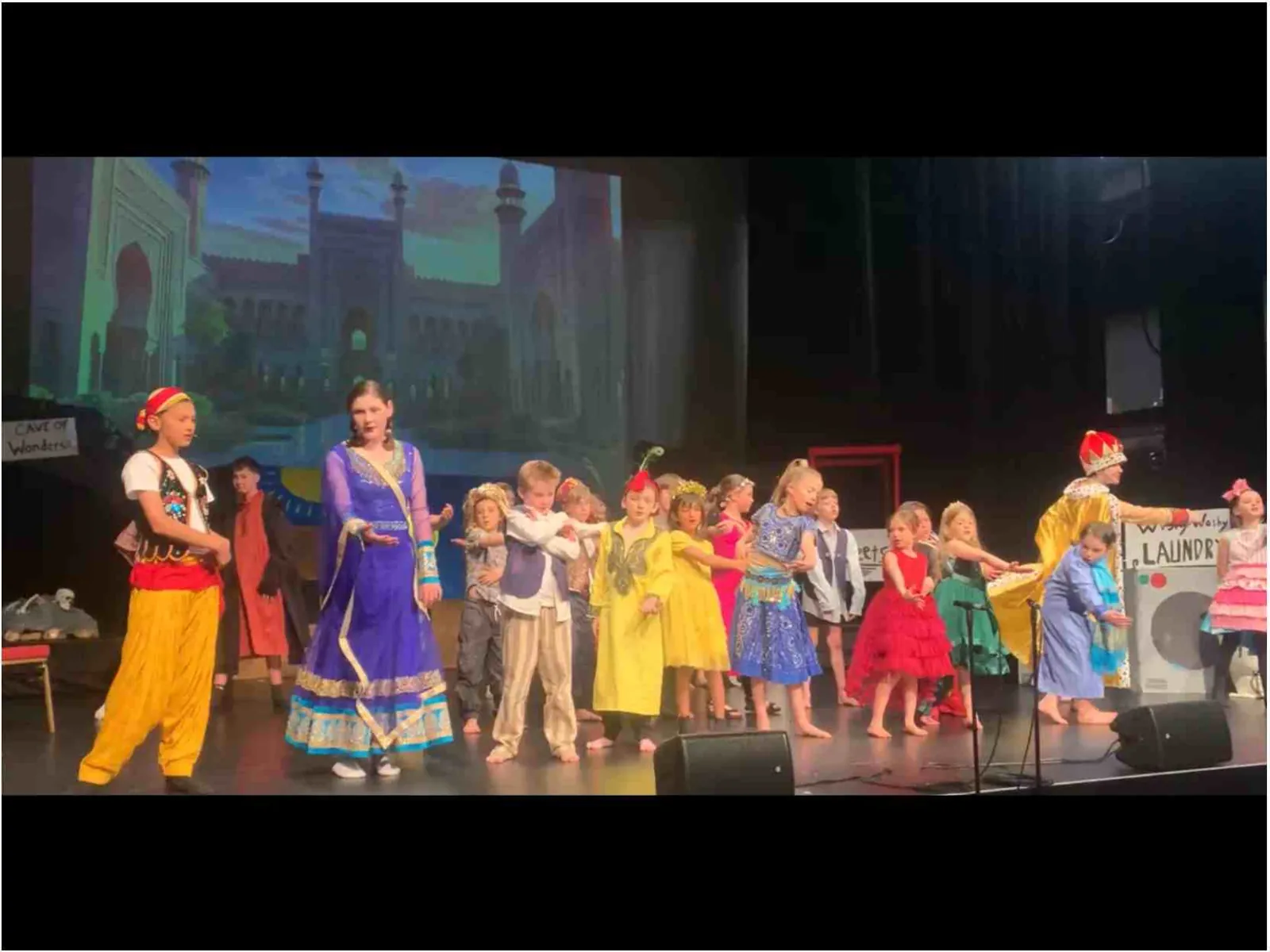 Carra students in colourful costumes performing their school production on stage